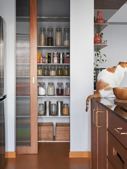 A sliding pantry door with a fluted glass panel reveals well-organized shelves. I design storage solutions like this to be both beautiful on the outside and highly practical on the inside.