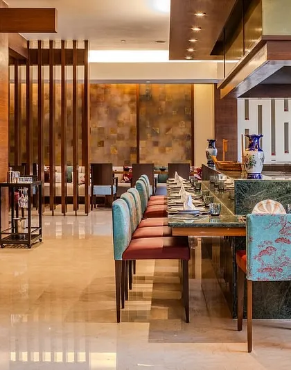 The teppanyaki counter at Tamari, where I used beautiful turquoise chairs with floral patterns to add a touch of elegance. The design combines rich wood, marble, and vibrant textiles to enhance the dining experience.