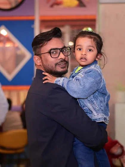 A father holding his daughter at her birthday party. These are the family moments that will be cherished for years.