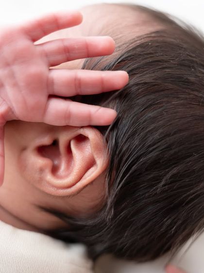 A close-up of a newborn's delicate ear and tiny hand. These detail shots are a beautiful way to remember just how small and perfect they were.