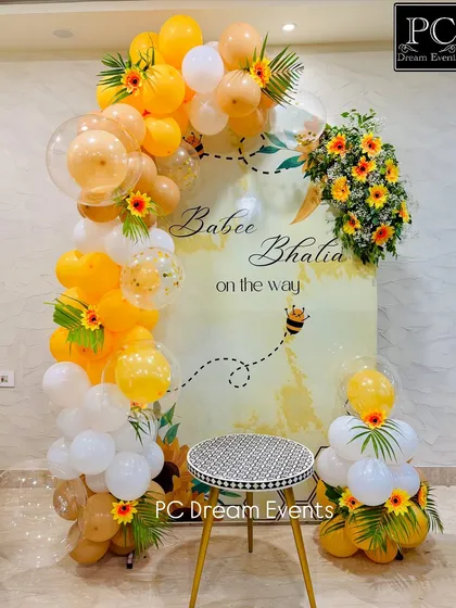 A "Sweet as can Bee" themed baby shower decoration. This setup features a cheerful yellow and white balloon arch, sunflower accents, and a custom backdrop for the mom-to-be.