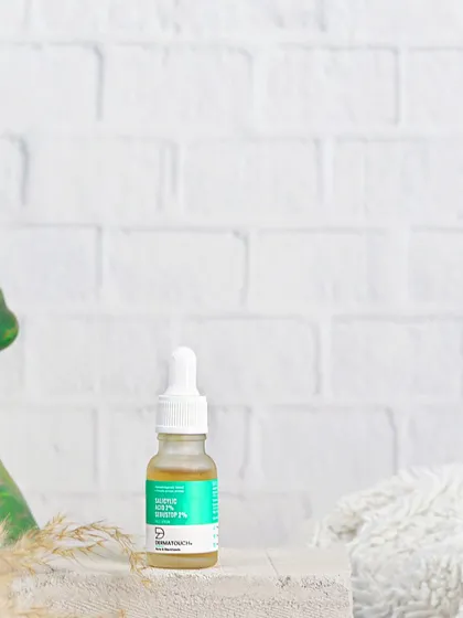 A minimalist composition of a Dermatouch serum bottle against a clean white brick wall, conveying a sense of clinical effectiveness and simplicity.