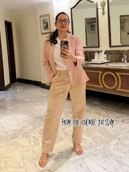 A classic formal look with a pink blazer and beige trousers. This mirror selfie showcases a polished and professional outfit, perfect for corporate events or meetings.