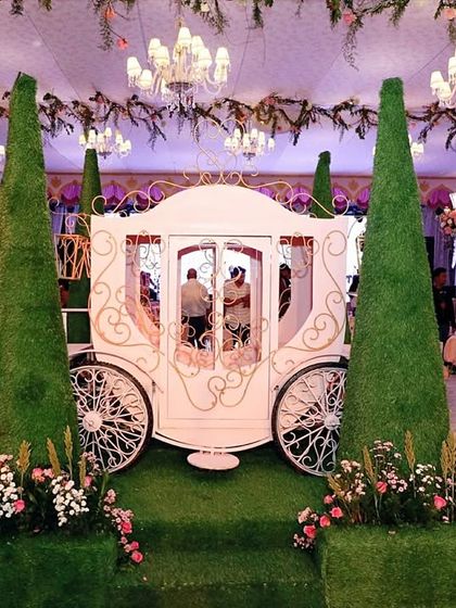 A fairytale entrance featuring a life-sized white princess carriage, flanked by topiary trees and floral arrangements. This is how you make a grand entrance.