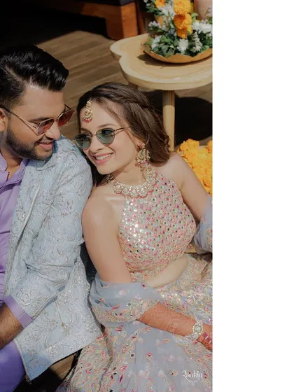 A happy, candid shot of the couple. The bride's subtle sunglasses add a cool, modern twist to her traditional-style lehenga, perfectly fitting the fun "carnival" theme.