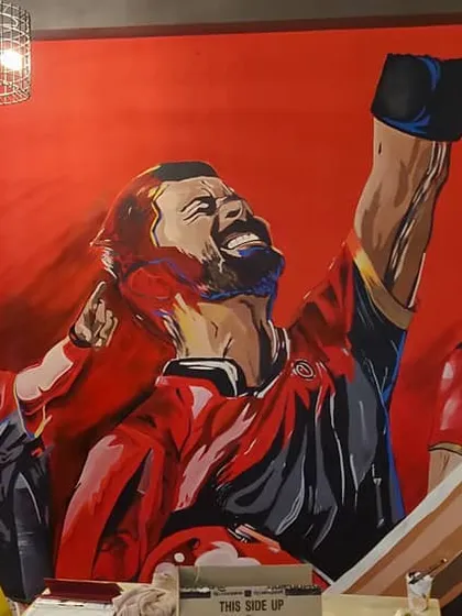 A view of the RCB mural before the furniture was set. The scale of the artwork dominates the room and sets a powerful, sporty theme.