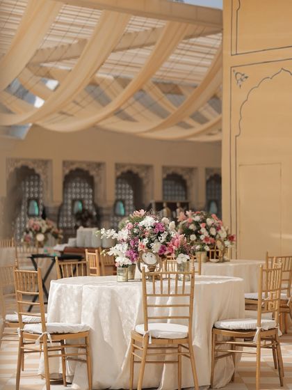 A view of the guest dining area, where the clean lines of the tables and chairs are softened by the flowing fabric ceiling and lush floral centerpieces.