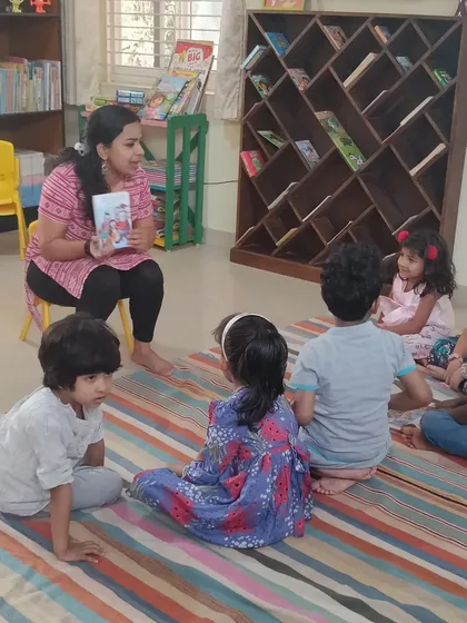 The storyteller holds up the book, sharing a story about sibling love and appreciation.