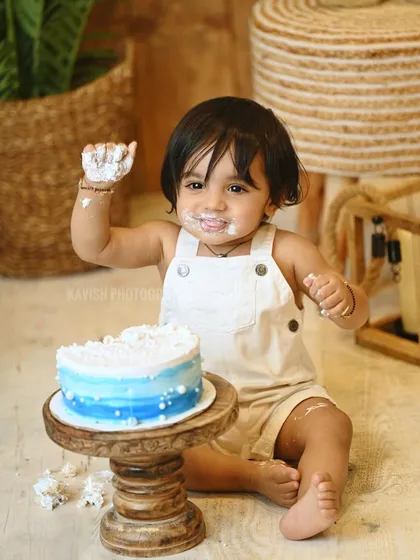 A playful shot of the baby showing off his frosting-covered hands.