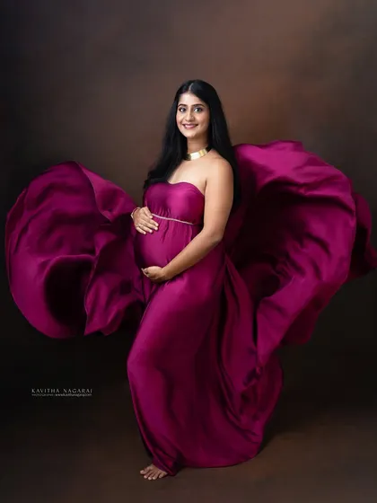 A stunning portrait of an expecting mother in a flowing magenta gown. The movement of the fabric adds a touch of drama and elegance to this celebration of motherhood.