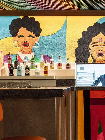 A detail of the bar at Khi Khi, where a pass-through window to the kitchen is cleverly integrated into the colorful wall carpet. This playful detail adds another layer to the bar's unique and immersive design.