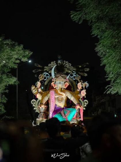A wide shot of the Sanpadya Cha Maharaja Aagman Sohala, showing the scale of the idol as it moves through the streets at night, surrounded by devotees.