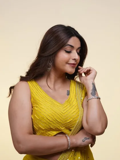 A close-up of the yellow pre-draped saree, showing the delicate embroidery on the blouse and the flattering drape of the skirt.