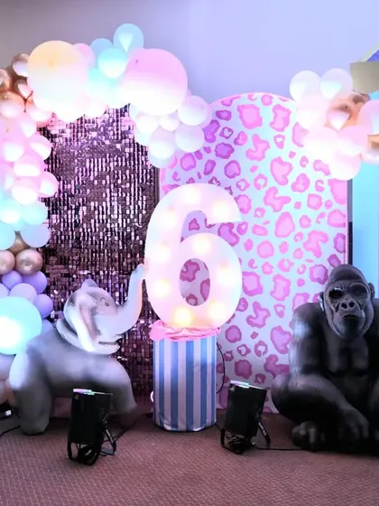 The main attraction at our pastel circus party. This setup features a large marquee number '6', a sequin backdrop, and life-sized animal props like a zebra, elephant, and gorilla.