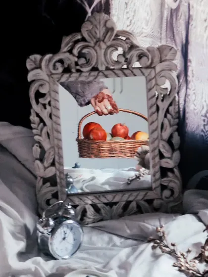 A creative and conceptual shot using a mirror to reflect a hand holding a fruit basket, blending art and photography.