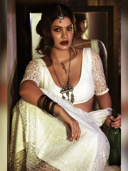 A rustic and moody portrait with a vintage feel. The styling, with heavy silver jewelry and a lace blouse, combined with the dark setting, tells a compelling story.