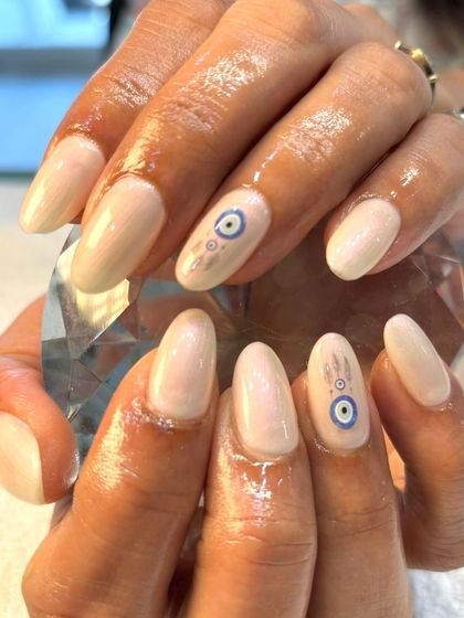 Ward off bad vibes with this stylish evil eye nail art. I hand-painted the delicate design on a shimmery, neutral base for a look that's both meaningful and chic.