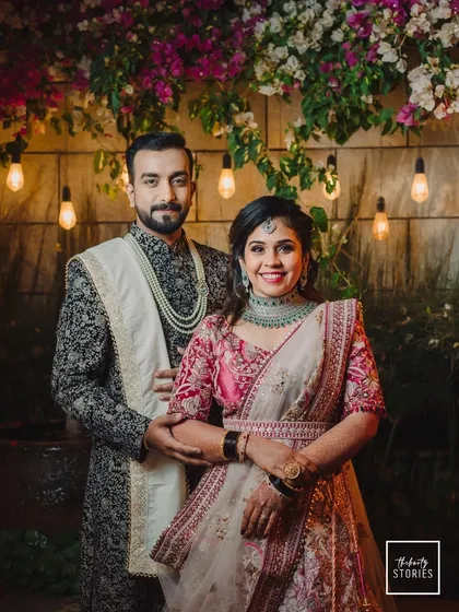 An elegant reception portrait of the couple. Their sophisticated outfits, the beautiful floral backdrop, and the warm lighting create a classic and timeless image.
