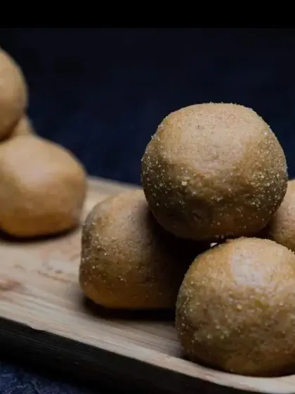 A simple, elegant shot of our Besan Ladoos stacked on a wooden board. This highlights their rustic, homemade texture. They are a perfect, wholesome sweet for any time of the year.