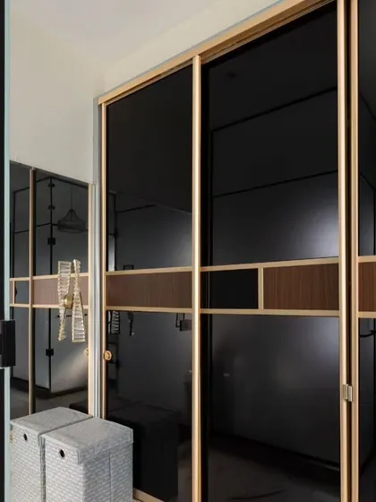 This walk-in closet and vanity area exudes luxury. I used a combination of black tinted glass sliding wardrobes and a bright, white vanity with marble-patterned walls to create a sophisticated and highly functional dressing space.