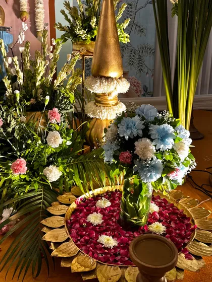 A traditional offering plate, or 'urli', filled with water and flower petals, sits at the base of a decorative setup for the Sai Sandhya. These details add to the spiritual ambiance of the event.