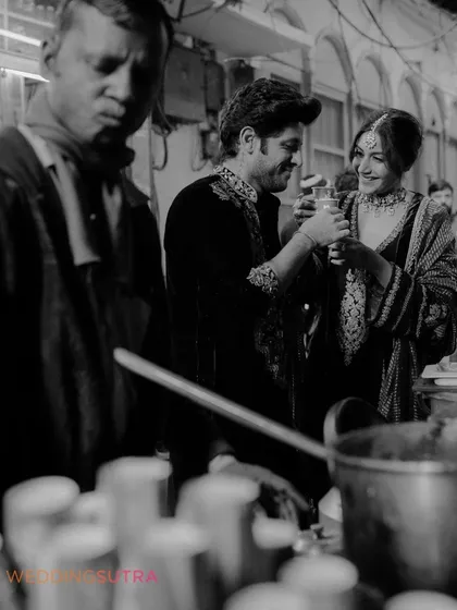 A candid, black and white moment from a food-themed pre-wedding shoot in the bustling streets of Old Delhi. This captures an authentic, shared experience that is unique to the couple.