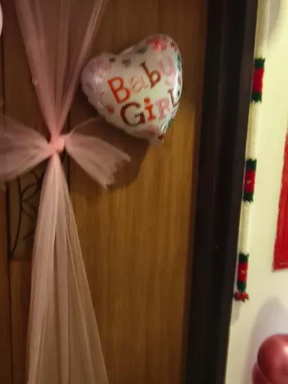 A close-up of the door decoration for a baby girl's welcome. I used a pink tulle bow and a heart-shaped "Baby Girl" foil balloon for an elegant touch.