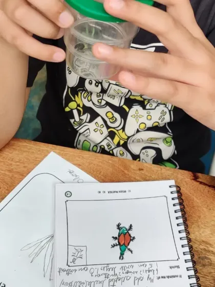 A young naturalist carefully sketches his insect discovery in his journal. This practice of observation and documentation is a key part of our learning process.