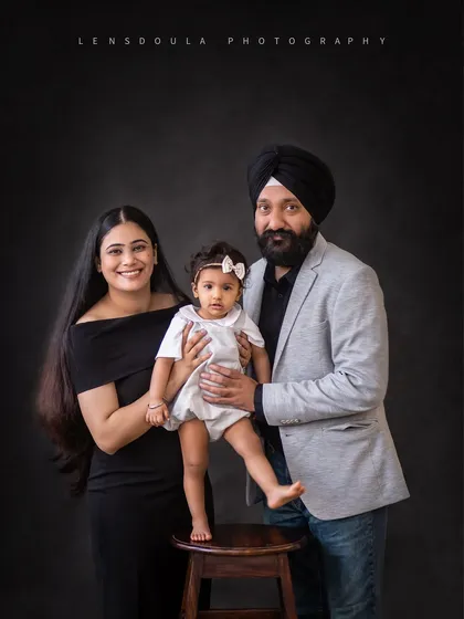 A fun and unique family pose, with the little one standing proudly on a stool. It adds a playful element to this classic studio portrait.