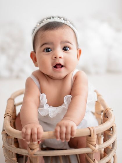 A beautiful baby girl in a wicker basket, looking right at the camera.