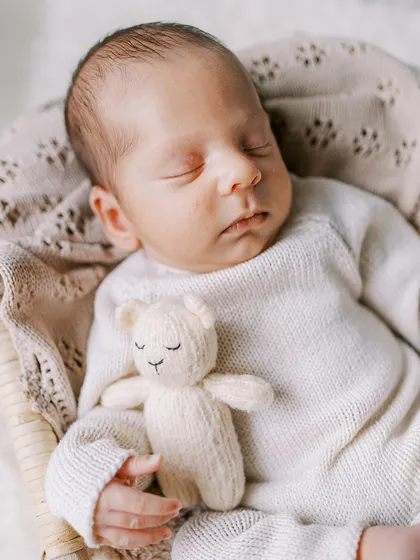 A peacefully sleeping one-month-old, cozy with his teddy bear. I use simple props and soft textures to create serene and classic newborn portraits.