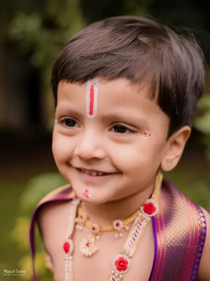 A close-up shot capturing the sweet, innocent smile of this little boy during his Krishna-themed session. The details, like the tilak and gentle expression, are what make these portraits so precious.