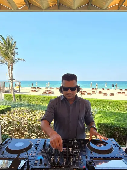 A daytime beach event requires a completely different energy. Here I am at a sundowner in Dubai, curating a relaxed yet groovy playlist as the sun sets over the ocean. It's all about matching the music to the mood.