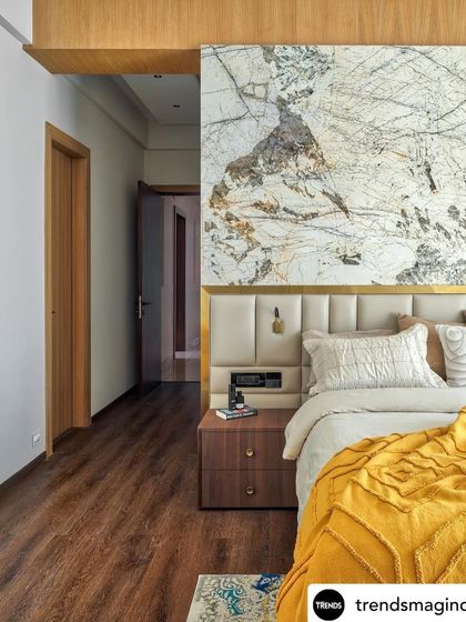 A bedroom from a feature in Trends Magazine, showing the stunning marble slab headboard and a pop of yellow from the throw blanket. The design feels luxurious and modern.