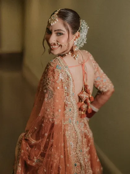 A smile that lights up the room. This over-the-shoulder shot of Muskan captures her happy and radiant personality, along with the beautiful back details of her bridal blouse.