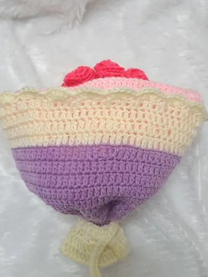 This is the bouquet form of a custom reversible doll, featuring a lovely blend of purple and cream-colored yarn. The base is designed to look like a wrapped floral bouquet.