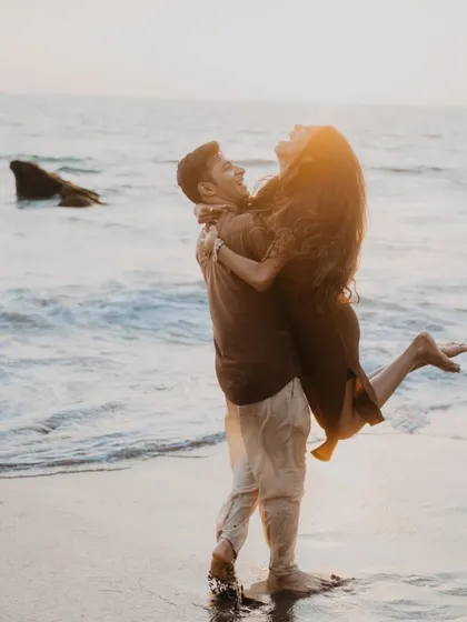 A joyful, candid moment of the couple laughing and playing in the waves. This photo perfectly captures the fun and carefree spirit of a beach pre-wedding shoot.