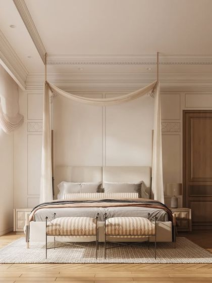 This bedroom design comes alive with elegant neutrals and warm wood accents. The four-poster bed with its delicate canopy creates a romantic focal point, while the large window floods the room with natural light.