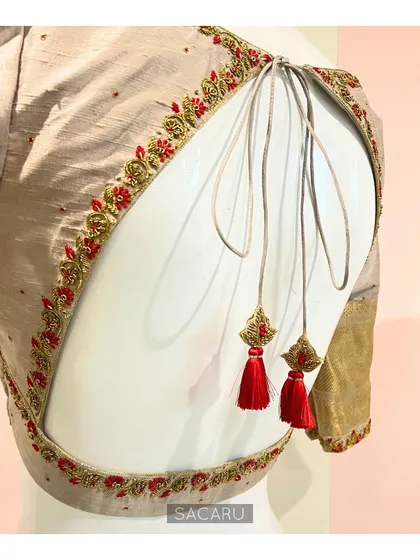 The full back view of the beige and red embroidered blouse, showing the beautiful cut and decorative tassels.