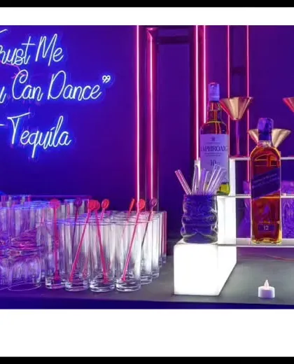 "Trust Me You Can Dance - Tequila." This neon sign says it all. We designed this vibrant, modern bar setup with glowing cubes and bold lighting to create the perfect party atmosphere.