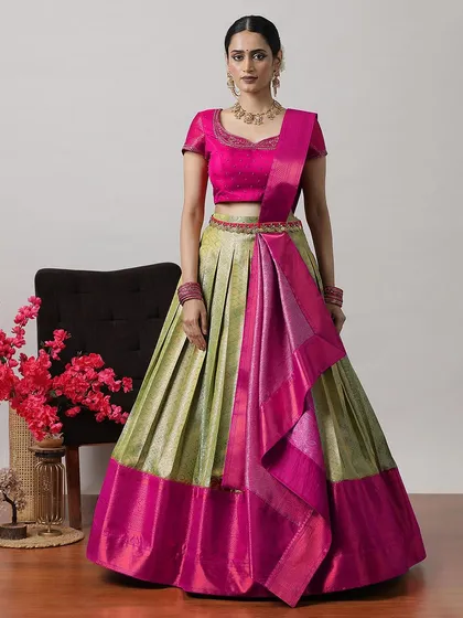 A traditional South Indian half-saree style lehenga in a beautiful combination of light green and pink silk with a rich zari border.