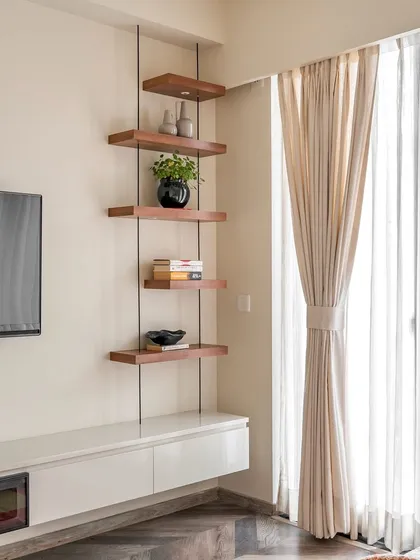 A functional and stylish corner in a 'Project Lily' bedroom, with a floating TV console and custom-built suspended wooden shelves for display.