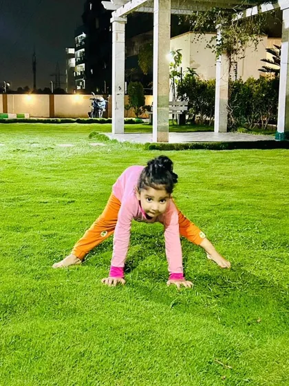 Taking our practice outdoors. Sometimes we move our mats to the grass to connect with nature. This playful wide-legged stance shows how yoga for children can be fun and liberating anywhere.