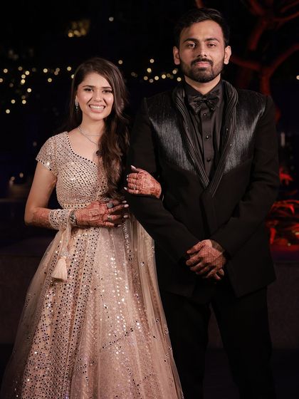 The full shot of the couple. Her side-parted waves complement her shimmery lehenga beautifully.