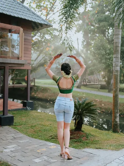 A modern take on a getting-ready shot, with bride Neha posing in her traditional blouse and shorts. This shows her fun-loving spirit before the main event.