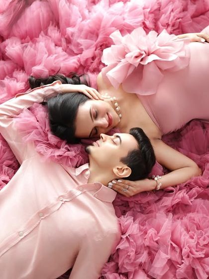 An intimate top-down view of the expecting couple, nestled in the soft ruffles of the pink gown. This creative angle captures a unique and romantic perspective.