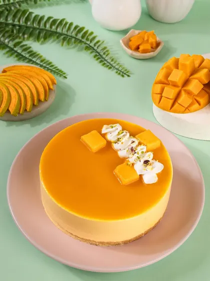 A top-down view of the mango cheesecake, showing the glossy surface and delicate decorations. This angle is great for showcasing the artistry of the dessert.