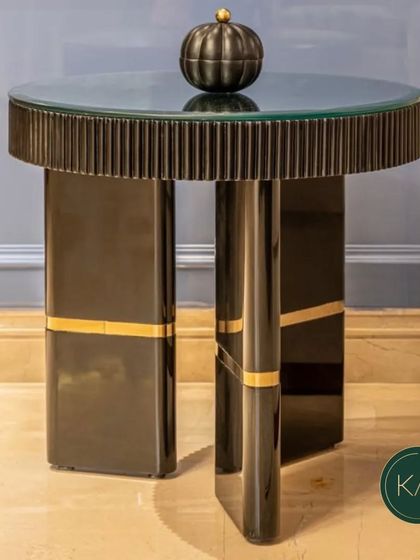 This modern side table features a fluted black base with gold-finished accents and a glass top. It's a chic and sophisticated piece, perfect for placing next to a sofa or armchair.