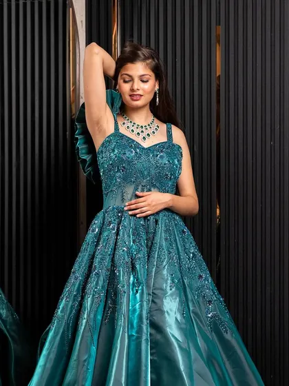 A model poses in the teal green ball gown, showing off its flattering silhouette and rich color. Rent this look to feel glamorous and confident.