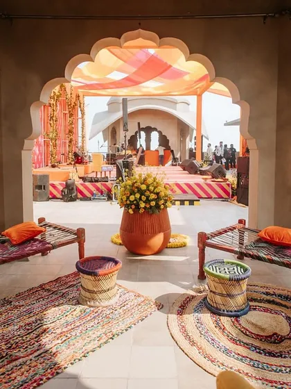 A cozy seating nook with traditional 'charpai' beds and colorful woven stools ('moodas'). This setup for the 'Jaipur Wali Haldi' was designed to evoke a sense of nostalgia and rustic charm.